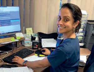 Dr Priya Krishnan in her consulting room in front of her computer.